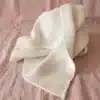 White textured towel draped over a pink fabric backdrop on a flat surface