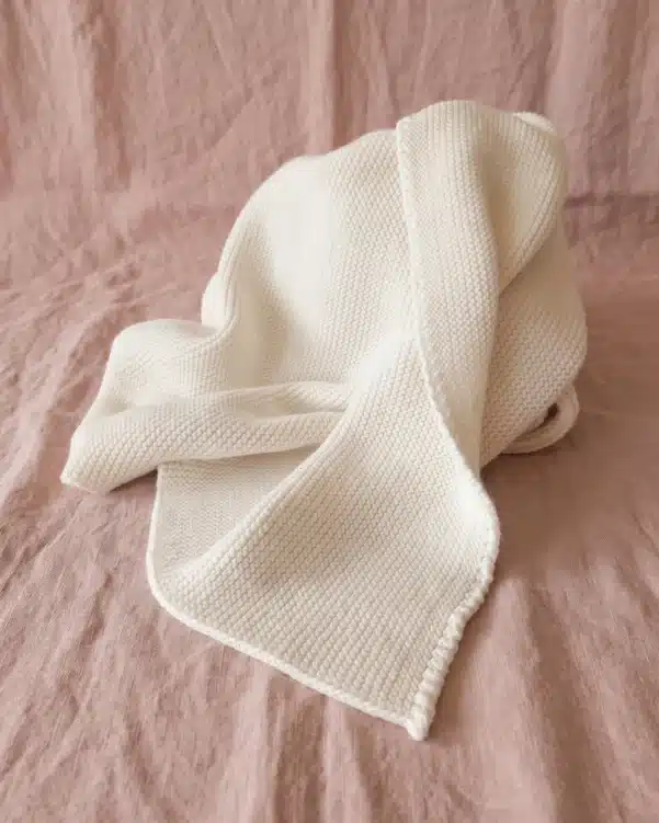 White textured towel draped over a pink fabric backdrop on a flat surface