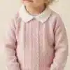 Young child wearing a soft pink knit sweater with a white Peter Pan collar, standing indoors.